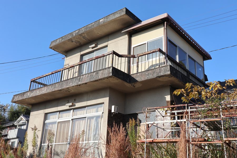 外壁が黒ずみ、手すりが錆びて傷んだ空き家